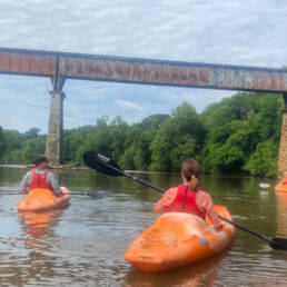 Individuals Kayaking under Bridge